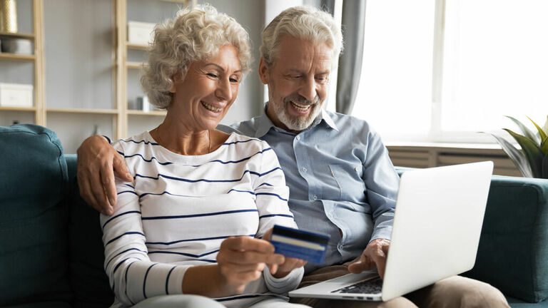 Elderly couple in front of a laptop holding a credit card